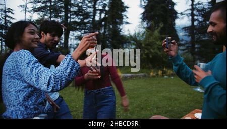 Group of young Indian friends drinking and dancing during an outdoor party Stock Photo