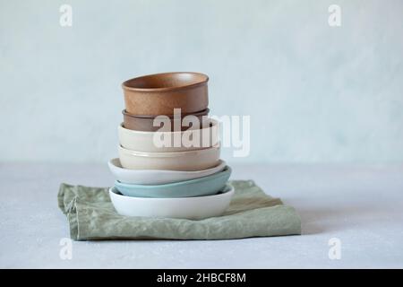 stack of ceramic and sandstone empty bowls of natural colors on green textile linen napkin Stock Photo