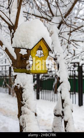 a small bird house covered with snow hangs from a tree in winter. High quality photo Stock Photo