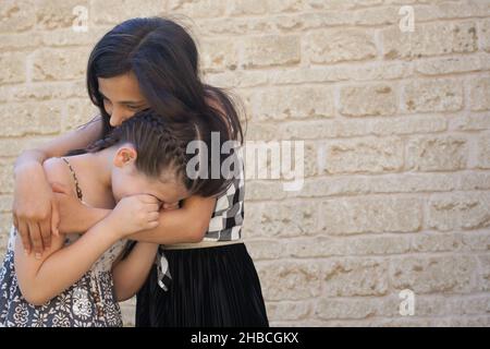 As one girl cries her older sister comforts and supports her Stock Photo
