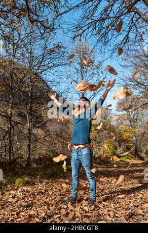 young man plays with yellow leaves falling down. vertical composition Stock Photo