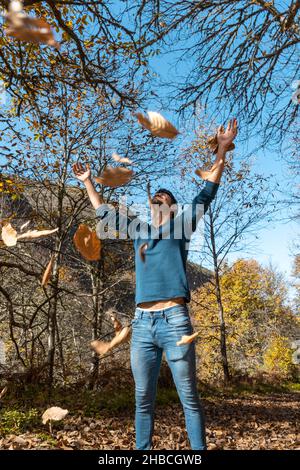 young man plays with yellow leaves falling down. vertical composition Stock Photo