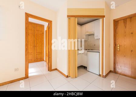 Apartment with small kitchen, bedroom with pine wood wardrobe and white tiles Stock Photo