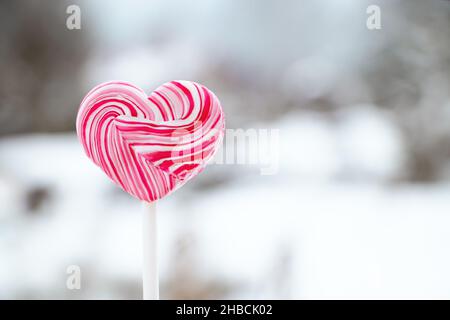 Heart shaped pink lollipop. Caramel candy on a stick. Sweet gift for valentines day. Stock Photo