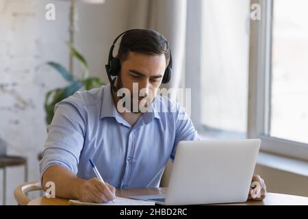 Focused young man studying distantly at home. Stock Photo