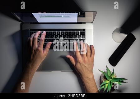 A man works at a computer at night, top view. Stock Photo
