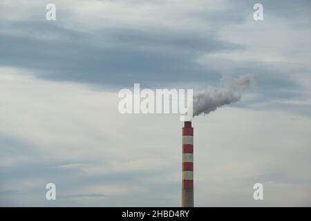 Factory chimney or tower with smoke coming out. Factory pipe pollutes the air in an industrial area. Global warming, polluted air. Stock Photo