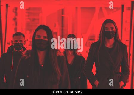 Healthcare, covid-19 concept. Image with red gradient mat color style of group of people walking at urban area in protective face masks during coronav Stock Photo