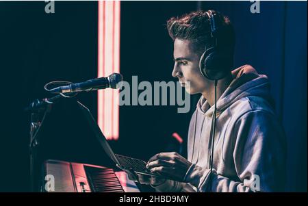 Young man in headphones behind the musical keys with a laptop. Stock Photo
