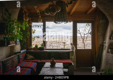 Inside view from the cave with home furniture and cat sitting by the window. Traditional Cappadocia cave interior for a living. Stock Photo