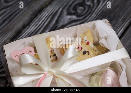 Marshmallow sandwiches decorated with chocolate and freeze-dried strawberries. Zephyr in the form of tulips. In a gift box. Close-up shot. Stock Photo