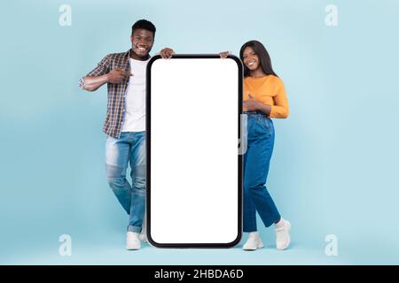 Couple showing white empty smartphone screen leaning on display Stock Photo