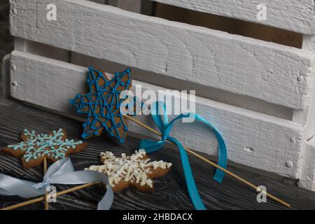 Gingerbread cookies in the shape of a snowflake. Decorated with sugar glaze. Gingerbread cookies on a stick in the shape of a snowflake. Lie on black Stock Photo