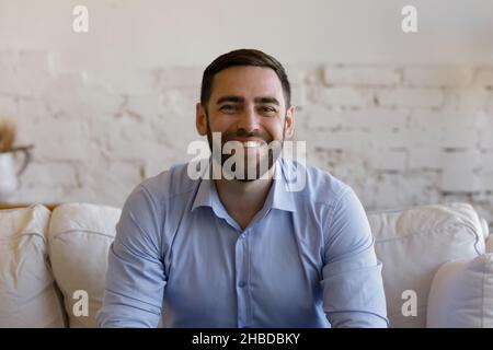 Portrait of smiling young man sitting on couch. Stock Photo