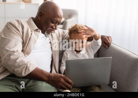 African American Grandpa And Grandson Video Calling Via Laptop Indoor Stock Photo