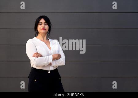 serious businesswoman looking at camera with her arms crossed, concept of successful entrepreneur and urban lifestyle, copy space for text Stock Photo