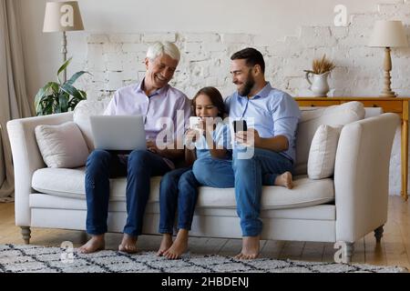 Happy relaxed multigenerational family using different gadgets.