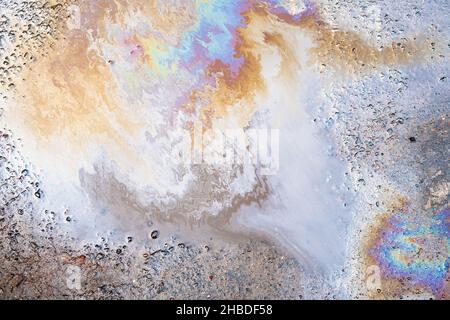 Beautiful iridescent stains of gasoline or oil in a puddle. Petrol on the asphalt a big polluted puddle water. Stock Photo