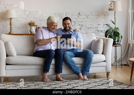 Happy young man and old father using digital tablet. Stock Photo