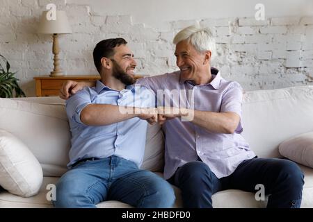 Happy young man bumping fists with old father. Stock Photo