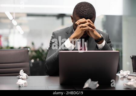 Tired black manager suffering from burnout, working on laptop Stock Photo