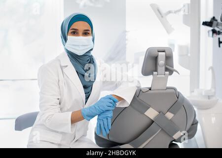 Muslim Women Jobs. Female Dentist In Hijab And Mask Posing At Workplace Stock Photo