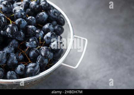 Sweet black grapes in a metal bowl on a dark textured background. Top view Stock Photo