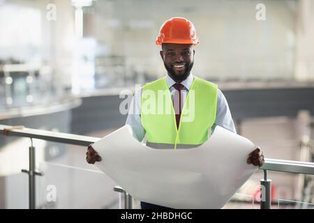 Happy african american man engineer holding paper drawing template Stock Photo