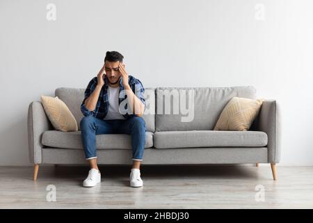 Arab man suffering from headache or migraine on couch Stock Photo