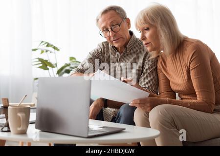 Mature Spouses Reading Papers And Documents Holding Letters At Home Stock Photo