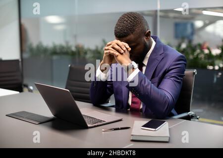 Frustrated black businessman sitting in front of laptop Stock Photo