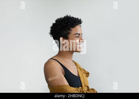 Dreamy young African American woman showing patch on arm. Stock Photo