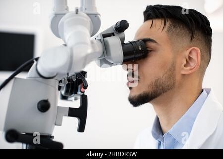 Closeup Shot Of Middle Eastern Medical Worker Using Dental Microscope In Clinic Stock Photo
