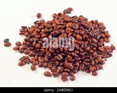 Coffee beans isolated on white background. Pile of roasted coffee beans scattered on white table. Stock Photo