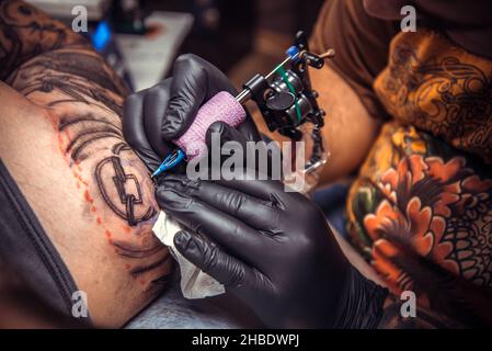 Professional tattoo artist doing tattoo in tattoo studio Stock Photo
