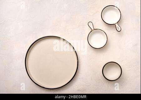 Empty plate and saucepans with black rim on light textured background. Top view Stock Photo