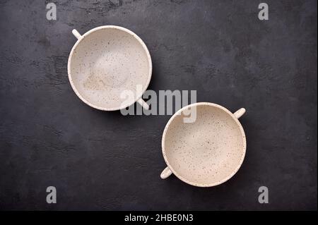 Top view on deep soup bowls with handles on black textured graphite background. Copy space Stock Photo