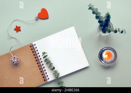 Mockup with blank spiral notepad, notebook. Eucalyptus in glass vase. Tea light candle. Top view, flat lay on mint green table. Eucalyptus twig as Stock Photo