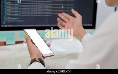 Close-up shot of Programmer hand using blank screen smartphone mockup. Stock Photo