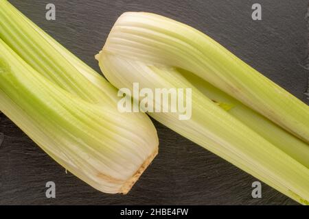 Two light green natural, juicy stalks of celery on a slate board, close-up, top view. Stock Photo