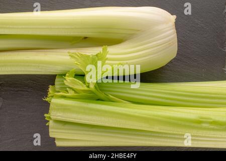 Two light green natural, juicy stalks of celery on a slate board, close-up, top view. Stock Photo