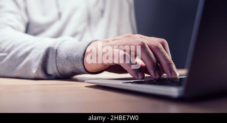 Closeup of male hand typing laptop computer keyboard with selective focus Stock Photo