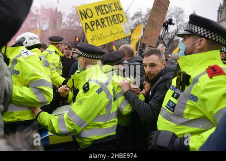 Police scuffling with protesters trying to prevent a blockade of the street, during the demonstration. Anti vaccine and anti vaccine pass protesters joined by opponents of Covid 19 restrictions, gathered at Parliament Square and marched through central London. Stock Photo