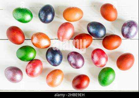 festive Easter background. multicolored painted eggs are scattered on a wooden white table. top view Stock Photo