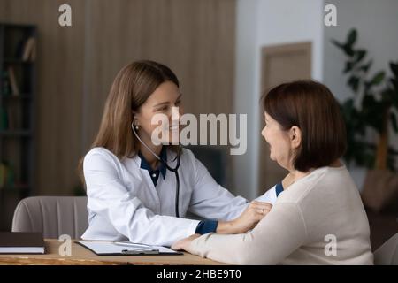 Friendly female doctor examine heart of senior woman using stethoscope Stock Photo