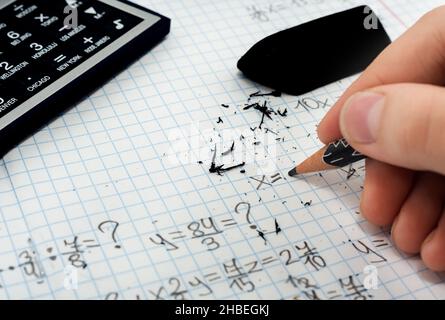 The hand writes with a pencil formulas and equations. Plaid background of formulas with empty space for inscriptions Stock Photo