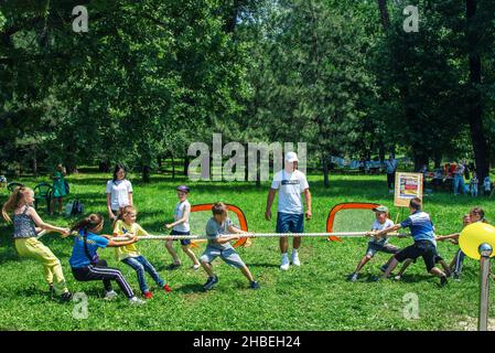 Zaporizhia, Ukraine- June 19, 2021: charity family festival - children- boys and girls - having fun, competing in tug of war game, on a meadow in a ci Stock Photo