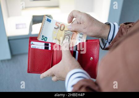 ATM machine and euros cash. Closeup of woman hand holding euro banknotes. Withdraw money from an ATM Stock Photo