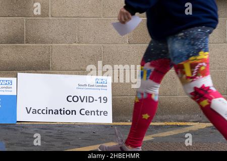 Greenwich London UK 19 December 2021. Southeast London clinical Commissioning group rolls out this weekend covid-19 vaccination for all eligible adults at The Valley, Charlton Athletic FC. Two young women dressed up on Stilts performing at the entrance to vaccine centre welcome people to get vaccinated to stop the surge of Omicron variant of coronavirus in the winter leading up to Christmas festive season. Credit: Xiu Bao/Alamy Live News Stock Photo