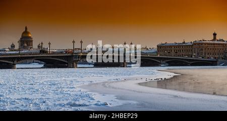 Winter panoramic view of St. Petersburg at sunset, Isaac cathedral and Blagoveshenskiy bridge on background, steam over frozen Neva river, sky of Stock Photo